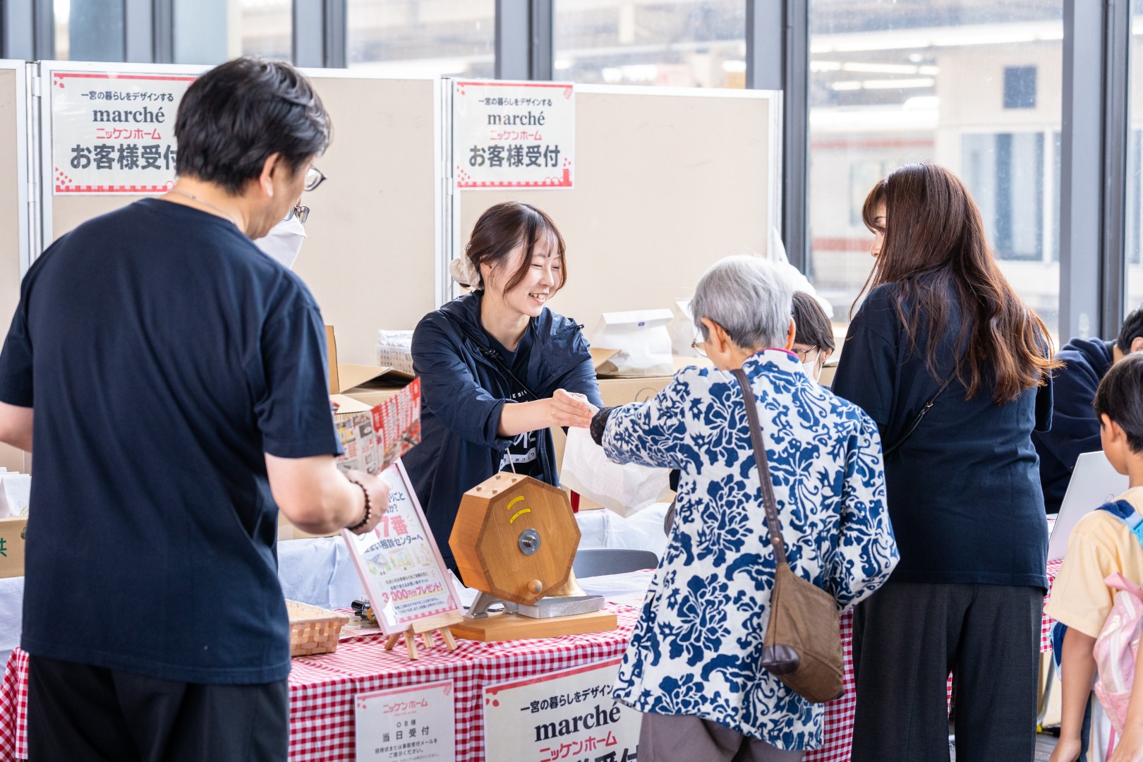 受付の抽選会で、スタッフが来場者に景品を手渡す様子