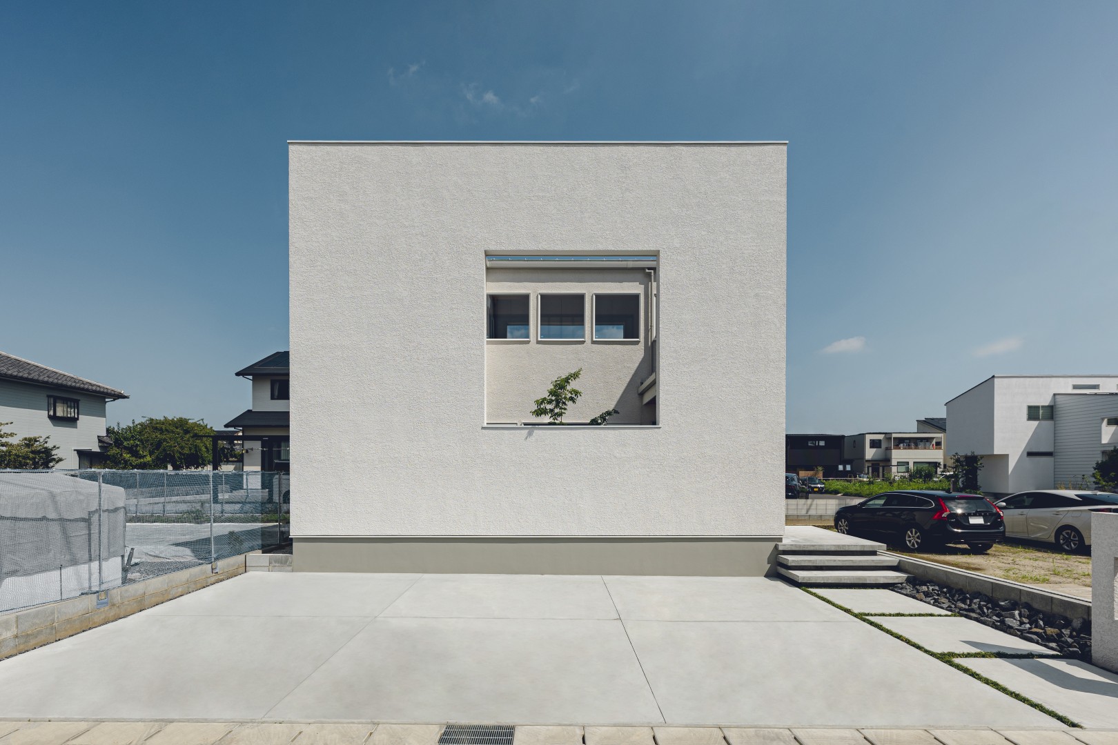 一宮市今伊勢町モデルハウス(2階建て)の外観。白い塗り壁の箱型で、2階に四角い開口がひとつ。手前はコンクリートの駐車スペース
